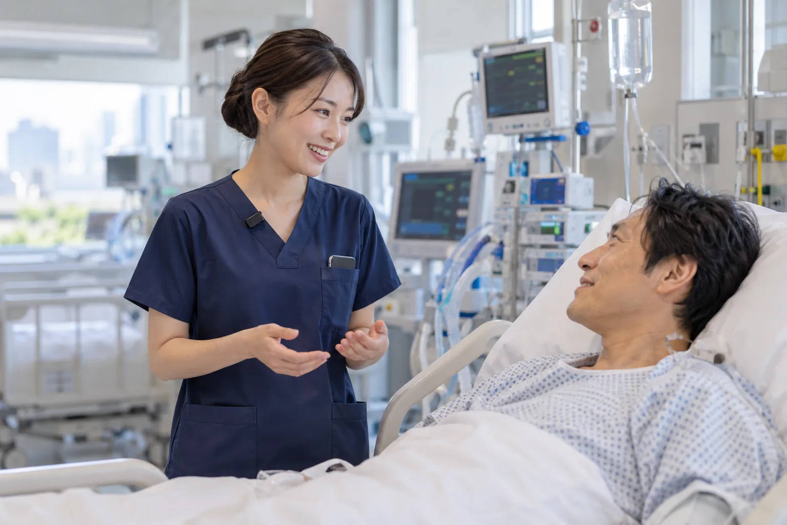 集中治療室で、看護師がベッドの患者さんに声をかけている