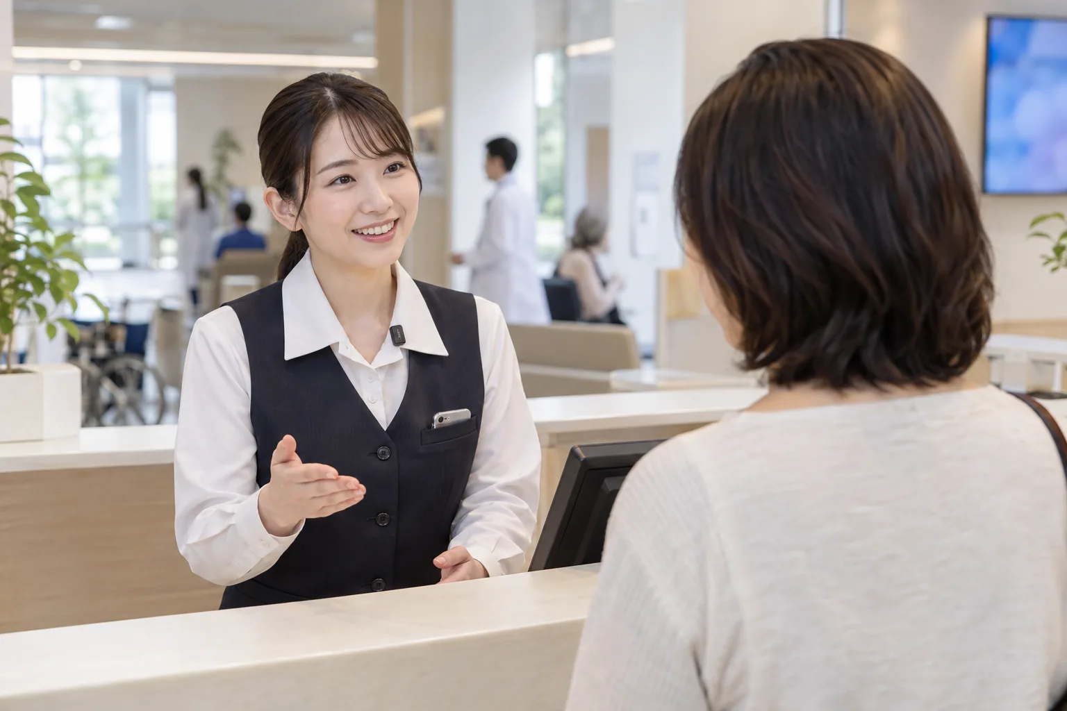 病院の受付で、事務員が来院した患者さんに応対している