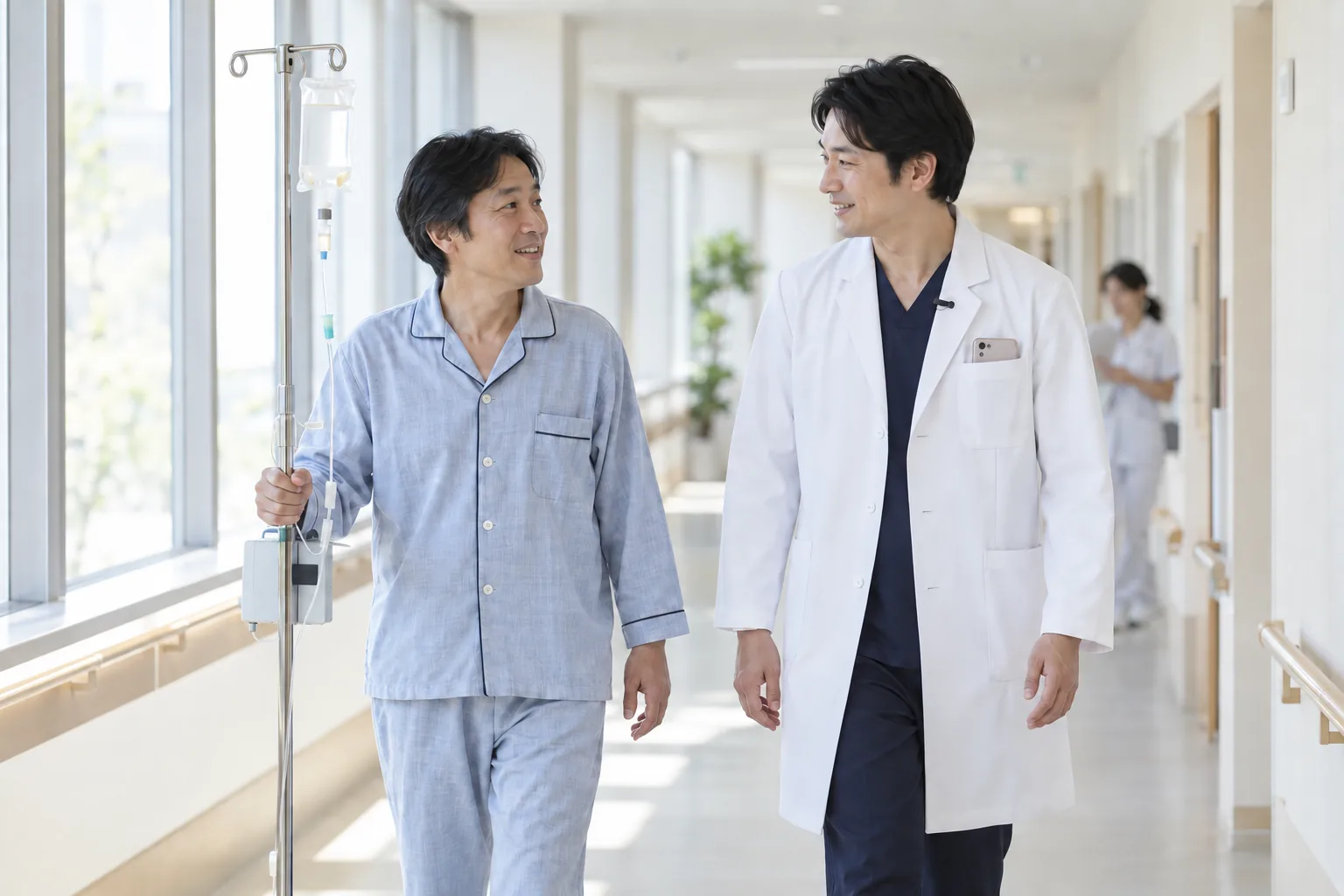 病棟の廊下で、医師が入院着の患者さんと立ち話をしている